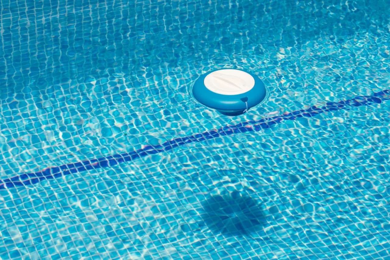 Chlorine floating chlorine dispenser for the treatment of water in swimming pools in the summer bathing season. Chlorine tablet container. Pool cleaning. copy space, unfocused background. pool pills